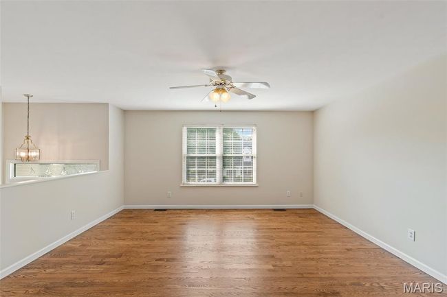 Unfurnished room featuring a chandelier, a ceiling fan, wood finished floors, and baseboards | Image 4