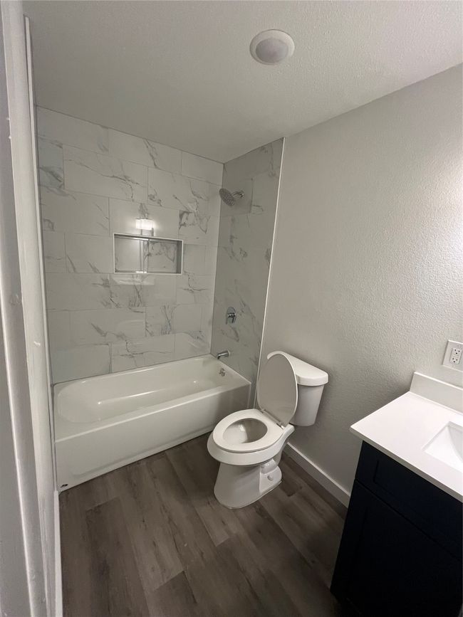 Bathroom featuring toilet, vanity, wood finished floors, shower / washtub combination, and a textured ceiling | Image 11