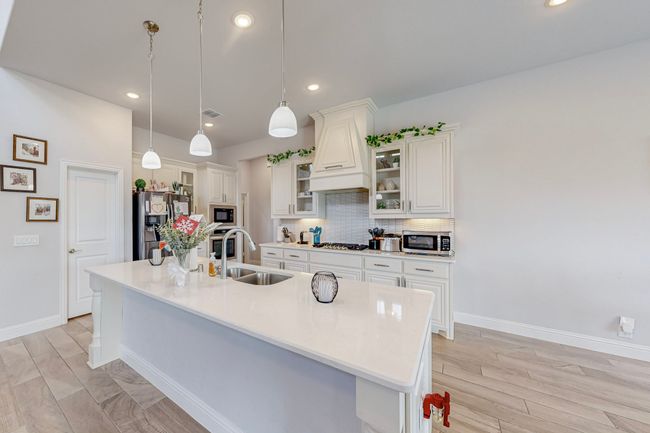 Kitchen with an island with sink, a sink, white cabinetry, tasteful backsplash, and stainless steel appliances | Image 8