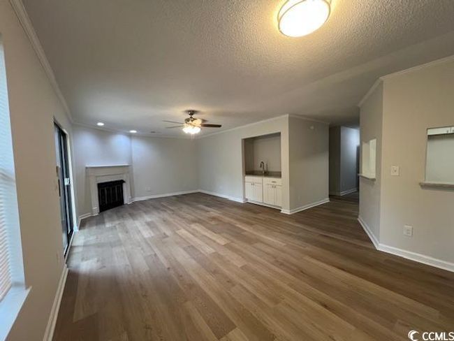 Unfurnished living room with crown molding, baseboards, ceiling fan, dark wood-style floors, and a textured ceiling | Image 31