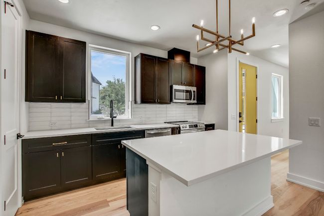 Kitchen with appliances with stainless steel finishes, a sink, tasteful backsplash, light wood-type flooring, and recessed lighting | Image 5