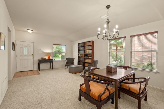Dining area with elegant chandelier and view into the kitchen through a large pass-through opening, maintaining an open and connected layout. | Image 7
