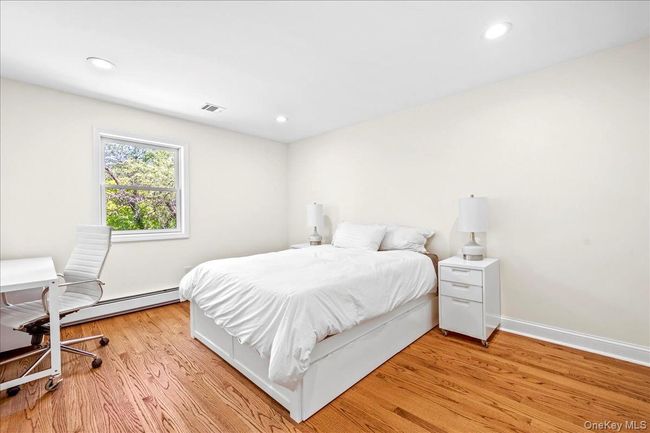 Bedroom featuring light wood floors, a baseboard heating, recessed lighting, and baseboards | Image 20