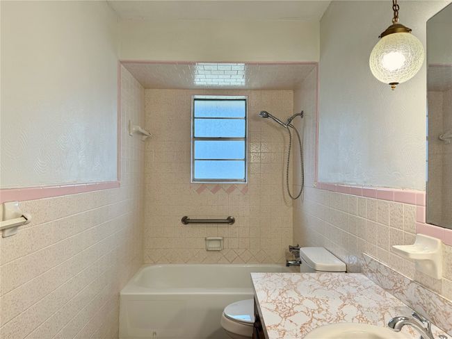 Full bathroom featuring tile walls, tiled shower / bath, vanity, and toilet | Image 22