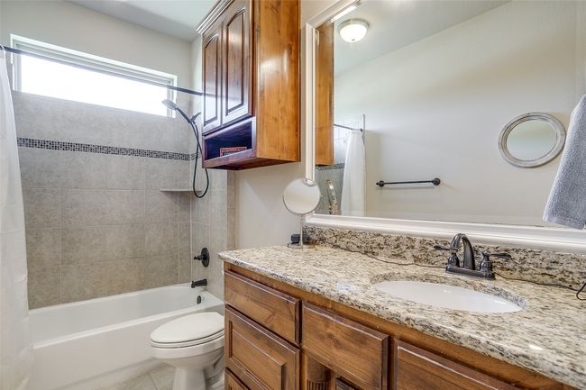 Bathroom with tile patterned flooring, shower / bathtub combination with curtain, vanity, and toilet | Image 20