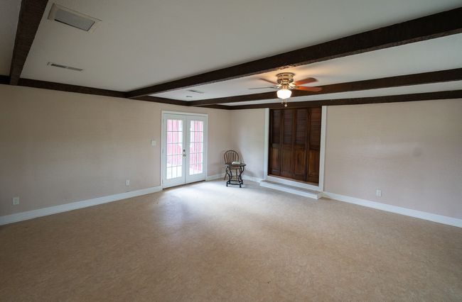 Spare room featuring beamed ceiling, french doors, a ceiling fan, and light carpet | Image 10