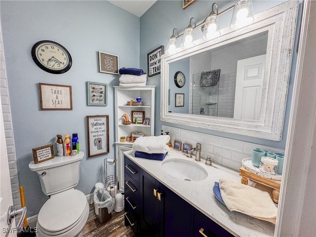 Bathroom featuring a tile shower, wood finished floors, vanity, baseboards, and decorative backsplash | Image 16