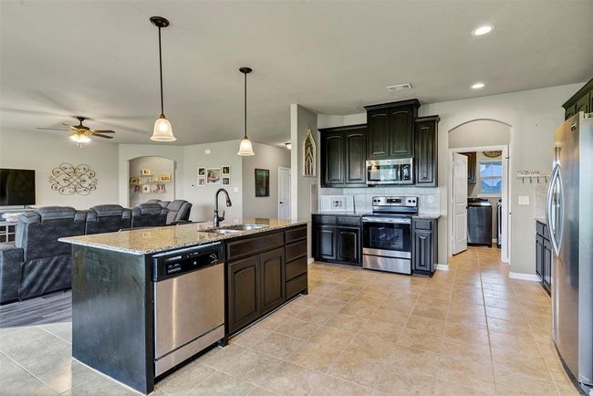 Kitchen featuring an island with sink, sink, light tile flooring, and stainless steel appliances | Image 12