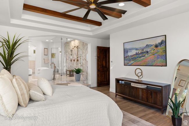Bedroom with a raised ceiling, arched walkways, connected bathroom, recessed lighting, and wood finished floors | Image 28