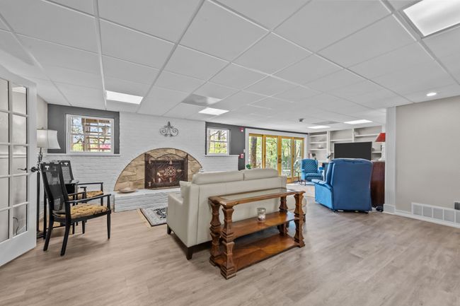 Living room with a drop ceiling, wood finished floors, brick wall, and visible vents | Image 10