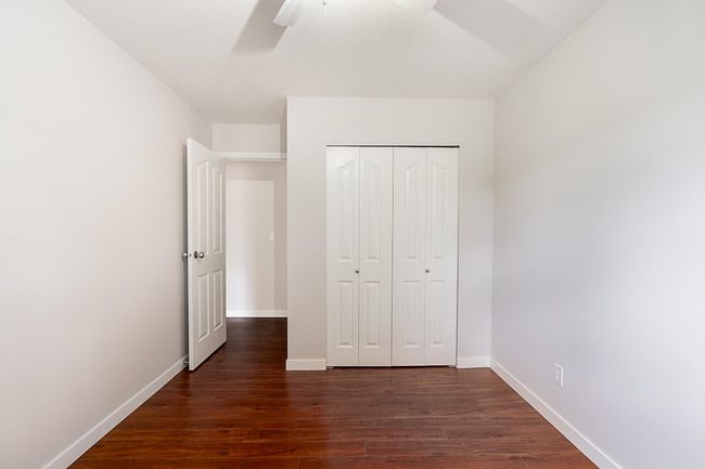 Unfurnished bedroom with dark wood-style flooring, a closet, and a ceiling fan | Image 19