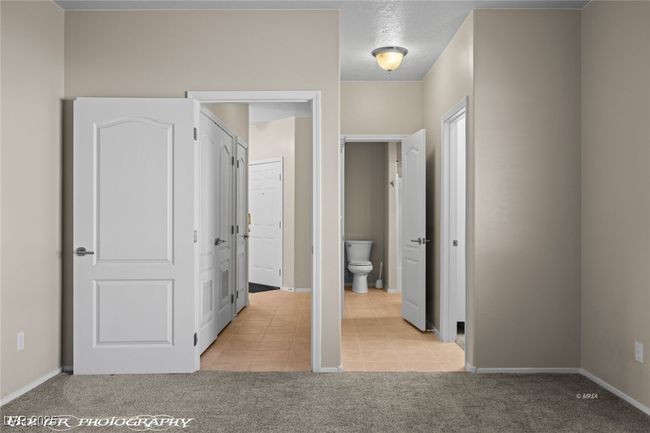 Unfurnished bedroom with light tile patterned flooring, baseboards, and light carpet | Image 23