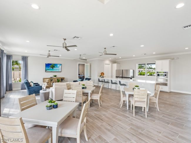 Welcome to the Community Clubhouse's inviting social room, where elegant tables and comfortable seating create the perfect ambiance for both engaging conversations and relaxing moments | Image 28