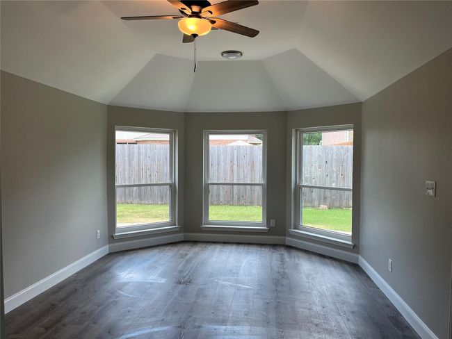 Empty room with ceiling fan, lofted ceiling, and dark wood-style flooring | Image 17