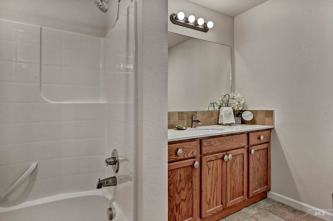 Full bathroom featuring vanity, backsplash, tub / shower combination, and tile patterned flooring | Image 11