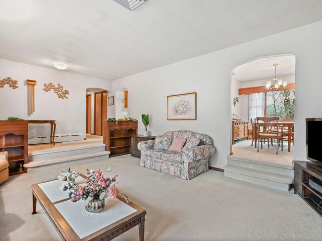 Living room featuring a chandelier, light colored carpet, and baseboard heating | Image 8