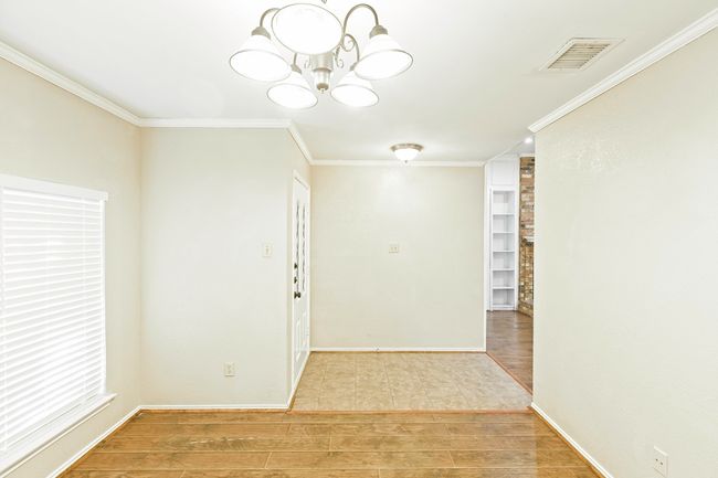 Empty room featuring crown molding, light wood finished floors, and a chandelier | Image 9