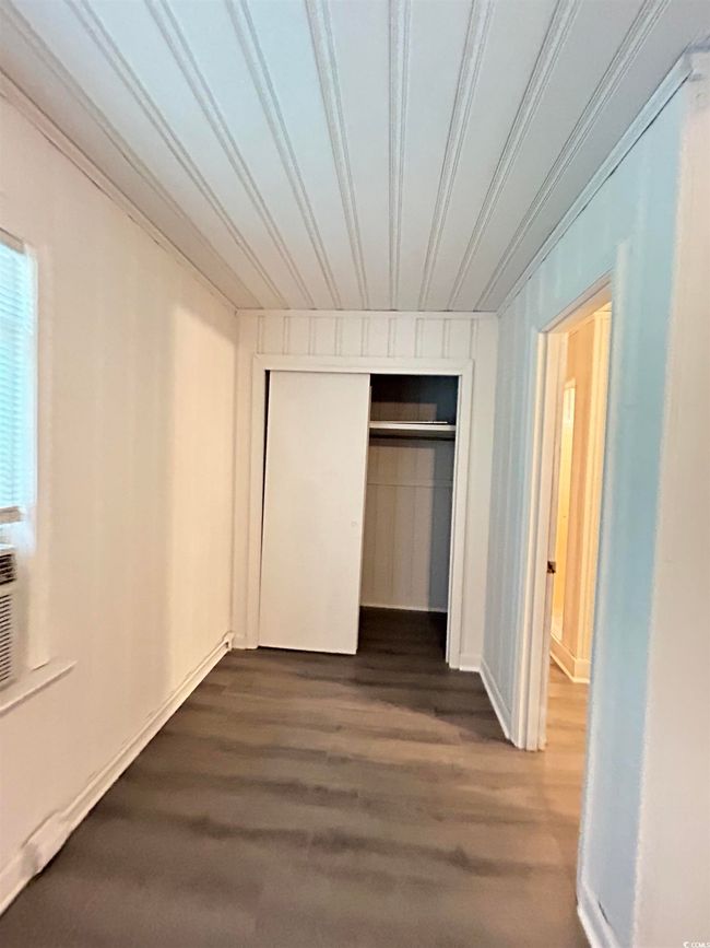 Unfurnished bedroom with a closet and dark wood-style flooring | Image 7