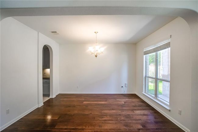 Unfurnished dining area featuring arched walkways, dark wood-type flooring, and a chandelier | Image 5