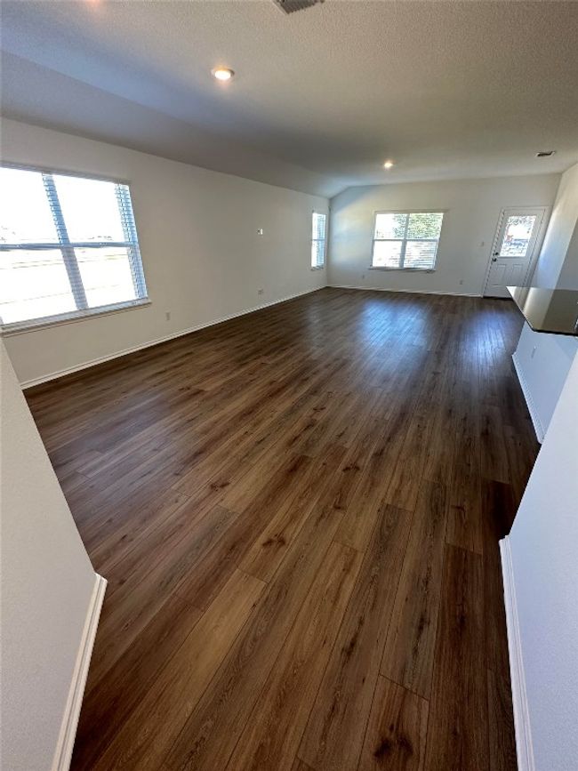 Unfurnished living room featuring baseboards, visible vents, and dark wood-type flooring | Image 7