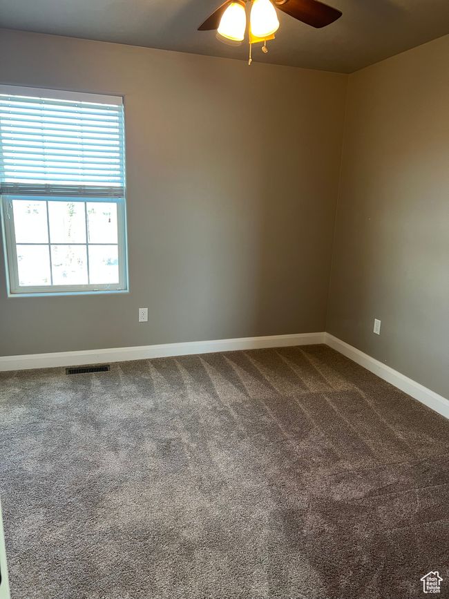 Empty room featuring a ceiling fan and dark colored carpet | Image 47