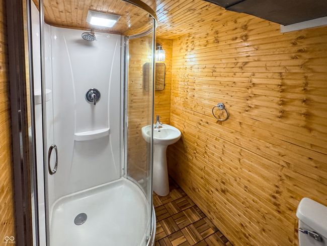 bathroom featuring wood walls, a stall shower, and wooden ceiling | Image 44