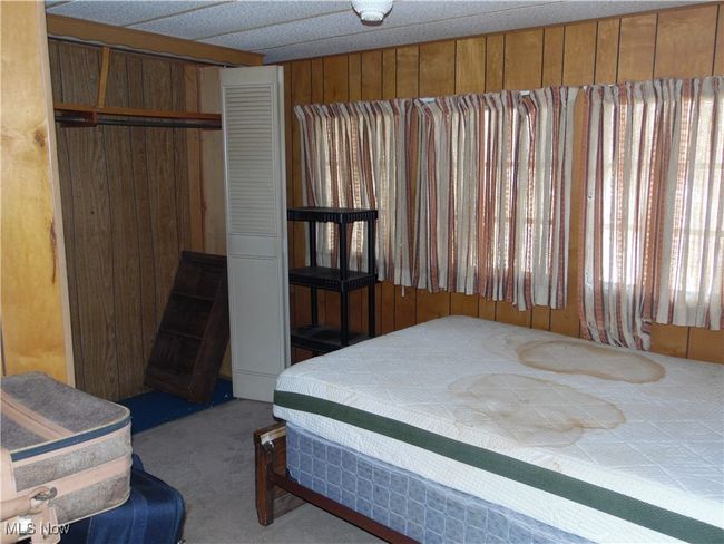 Bedroom with wood walls and carpet flooring | Image 11