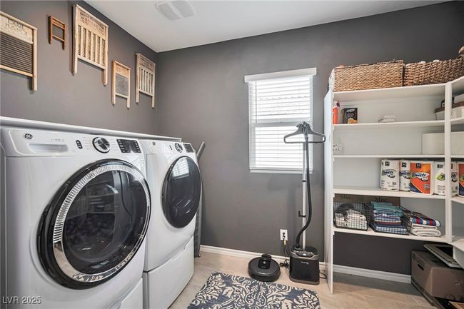 Laundry area with independent washer and dryer, light tile patterned flooring, baseboards, and laundry area | Image 15