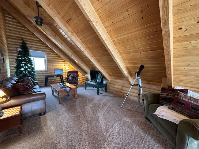 Carpeted living area featuring rustic walls, wooden ceiling, and vaulted ceiling with beams | Image 8