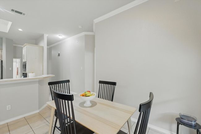 Dining space with baseboards, light tile patterned floors, a skylight, visible vents, and ornamental molding | Image 17