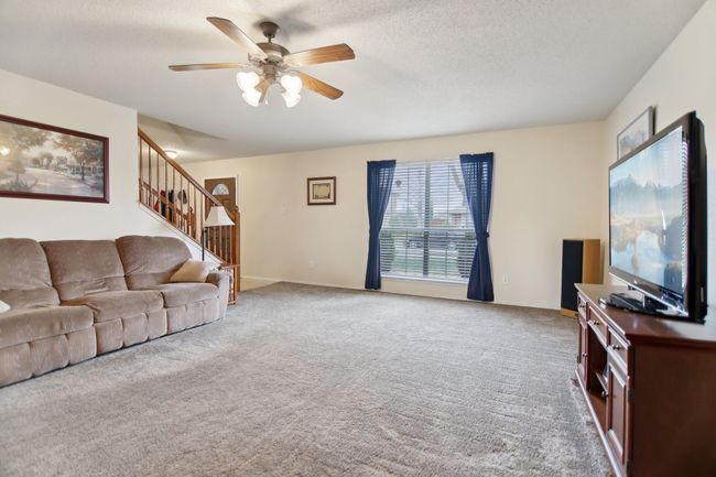Living room featuring stairway, a textured ceiling, baseboards, ceiling fan, and carpet | Image 7