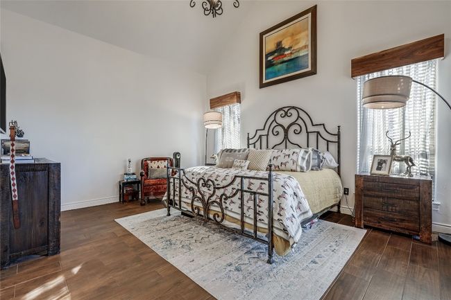 Bedroom featuring wood finished floors, baseboards, and high vaulted ceiling | Image 21