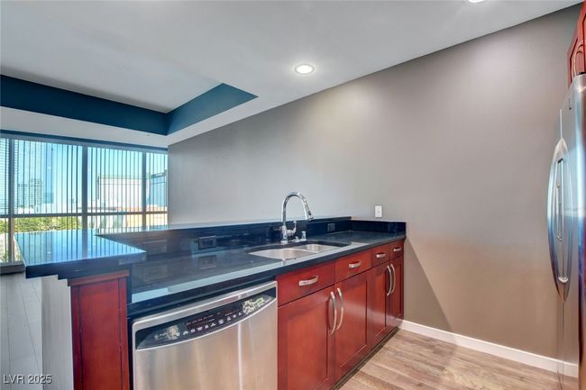 Kitchen featuring stainless steel appliances, reddish brown cabinets, a sink, light wood-type flooring, and baseboards | Image 8