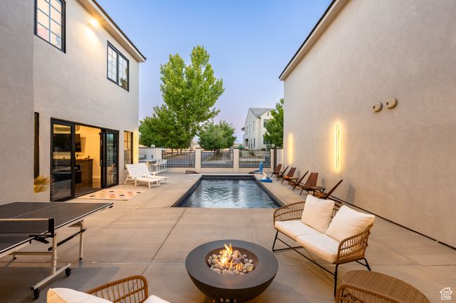 Pool at dusk with a patio area and an outdoor living space with a fire pit | Image 4