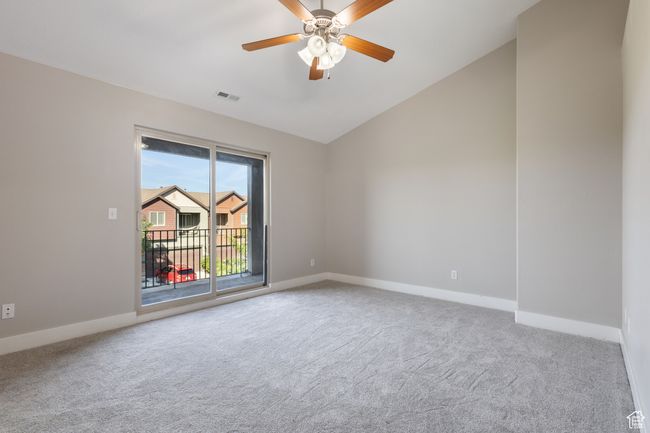 Carpeted empty room with vaulted ceiling and ceiling fan | Image 11
