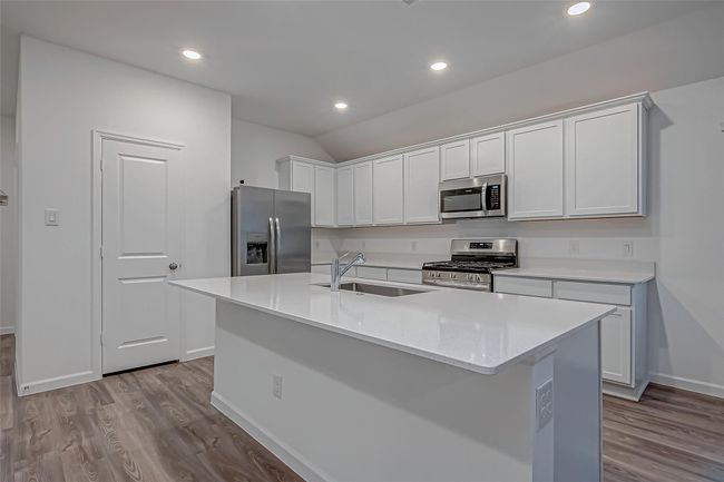 The open-concept kitchen is a chef’s dream, featuring a spacious island, gleaming granite countertops, a stylish tile backsplash, an under-mount sink, stainless steel appliances, and a walk-in pantry for ample storage. | Image 15