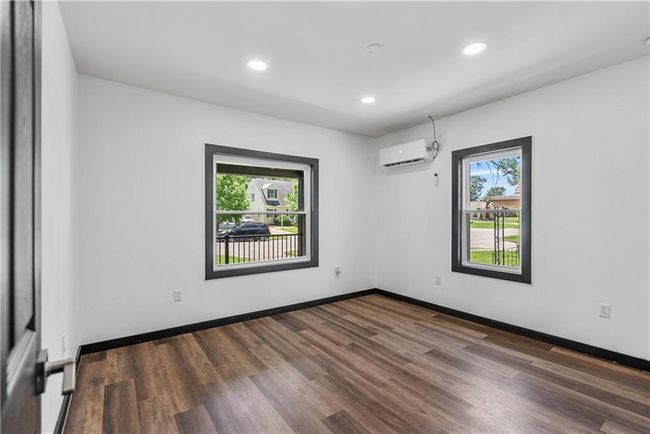Bedroom featuring a wall mounted AC, dark wood finished floors, baseboards, and recessed lighting | Image 27