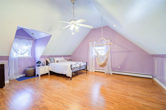 Bedroom 2 featuring light wood finished floors, baseboards, lofted ceiling, baseboard heating, and a ceiling fan | Image 26
