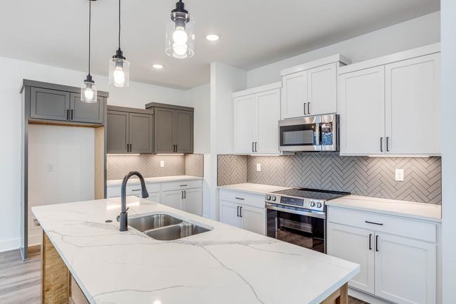 Kitchen with appliances with stainless steel finishes, a sink, an island with sink, pendant lighting, and light wood-type flooring | Image 8