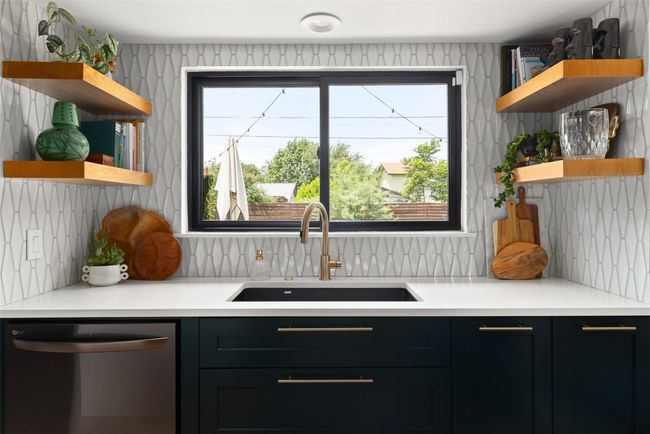 Prep area with additional sink over looking the backyard. Floating wood shelves and tile backsplash. | Image 15