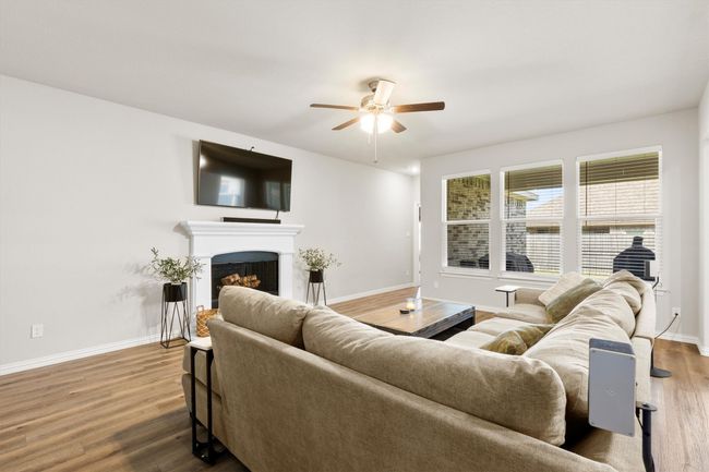 Living room with a ceiling fan, wood finished floors, and a fireplace | Image 8