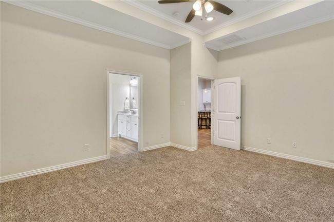 Unfurnished bedroom with light carpet, crown molding, ensuite bathroom, and ceiling fan | Image 16