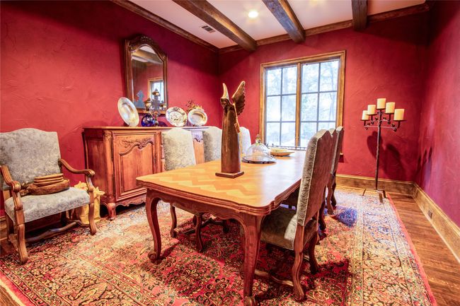 Dining space featuring a textured wall, baseboards, beam ceiling, visible vents, and wood finished floors | Image 11