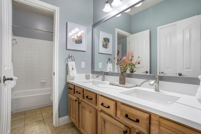 Full bath with double vanity, toilet, tile patterned flooring, and bathing tub / shower combination | Image 27