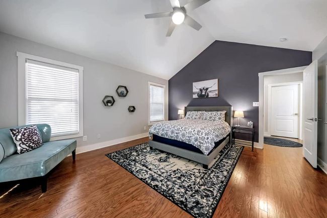 Primary Bedroom with vaulted ceiling, wood finished floors, multiple windows, and a ceiling fan | Image 21