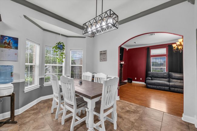 Dining space with crown molding, a chandelier, arched walkways, baseboards, and tile patterned floors | Image 4