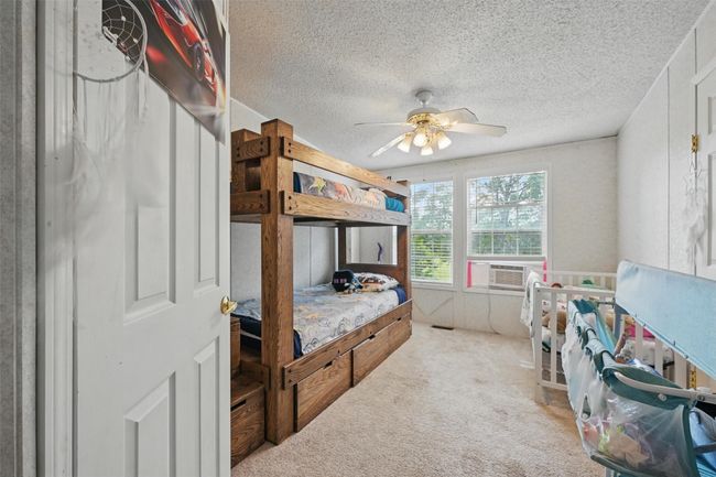 Carpeted bedroom with cooling unit, a textured ceiling, and a ceiling fan | Image 13