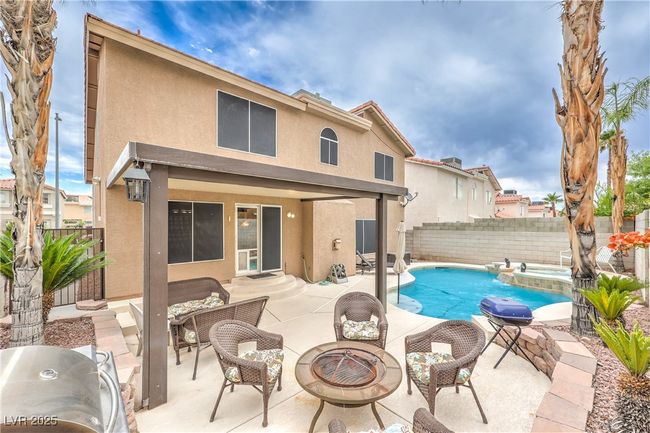 View of swimming pool with a fenced backyard, a patio area, a pool with connected hot tub, and an outdoor living space with a fire pit | Image 35