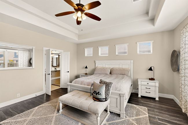 Bedroom featuring a raised ceiling, wood finished floors, baseboards, and ensuite bathroom | Image 13