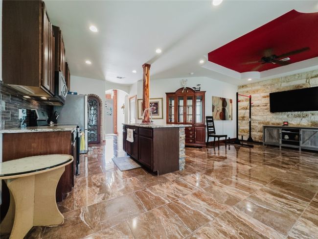 Kitchen with arched walkways, stainless steel microwave, decorative columns, a ceiling fan, and dark brown cabinetry | Image 14